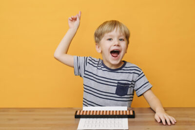 Little boy doing simple math exercises with abacus scores